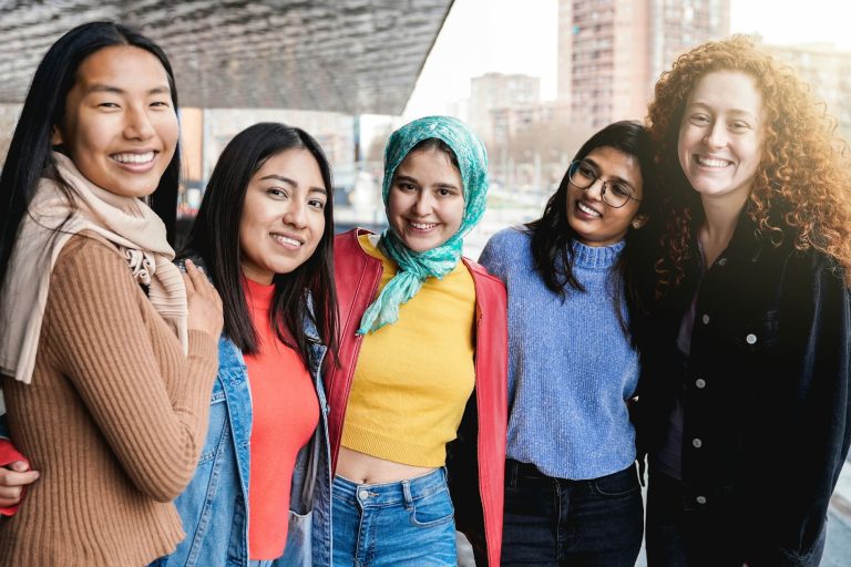 Diverse female friends having fun togehter on city street. Group of multiracial people smiling